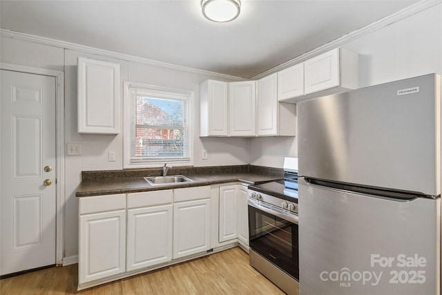 kitchen featuring a sink, white cabinetry, light wood-style floors, appliances with stainless steel finishes, and dark countertops