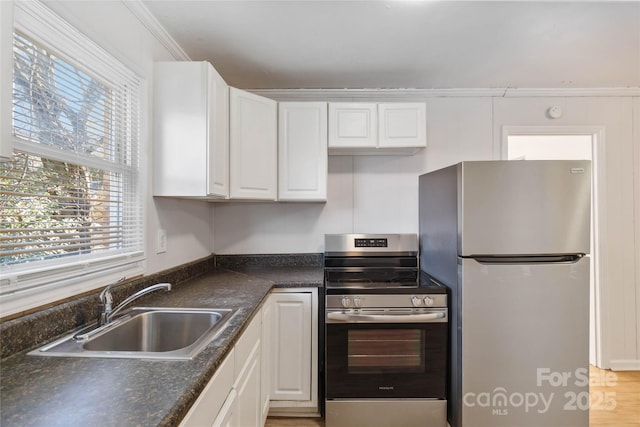 kitchen with dark countertops, white cabinetry, appliances with stainless steel finishes, and a sink