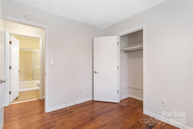 unfurnished bedroom with dark wood-type flooring, a closet, and baseboards