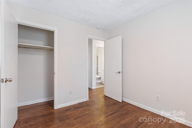 unfurnished bedroom featuring a closet, dark wood finished floors, and baseboards