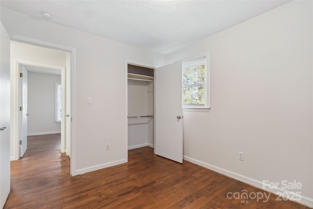 unfurnished bedroom featuring a closet, dark wood finished floors, and baseboards