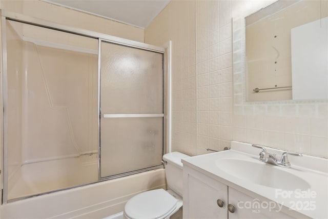 bathroom with toilet, shower / bath combination with glass door, vanity, tile walls, and backsplash