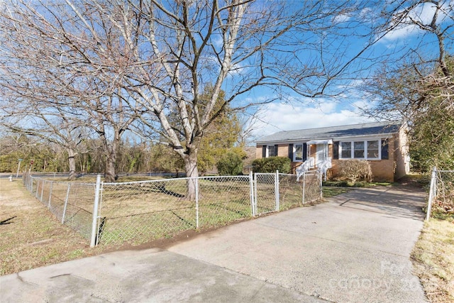 ranch-style home featuring a fenced front yard, concrete driveway, and brick siding