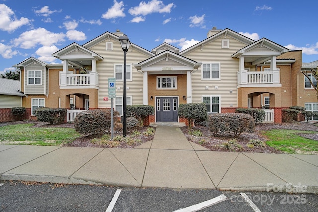 view of property featuring uncovered parking and brick siding