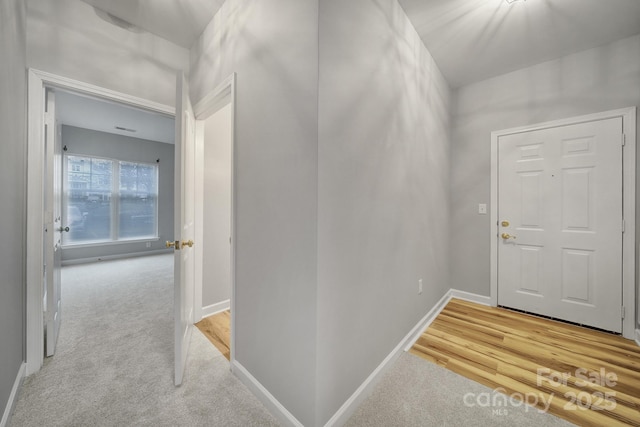 entryway featuring baseboards and light colored carpet