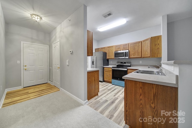 kitchen featuring visible vents, light countertops, brown cabinetry, appliances with stainless steel finishes, and a sink