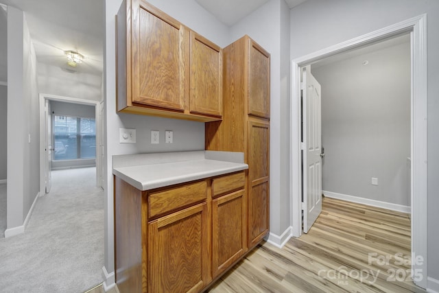 kitchen featuring light wood finished floors, baseboards, and light countertops