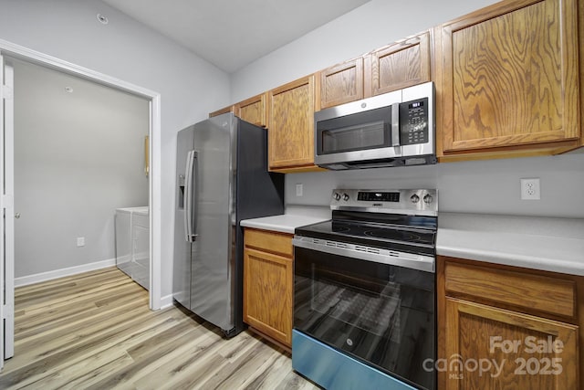 kitchen with stainless steel appliances, separate washer and dryer, light countertops, and light wood-style floors