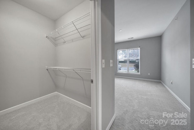 walk in closet featuring visible vents and light colored carpet