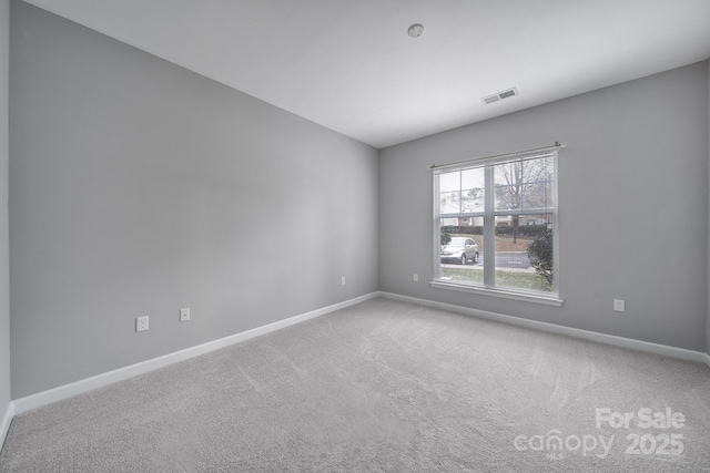 carpeted empty room featuring baseboards and visible vents