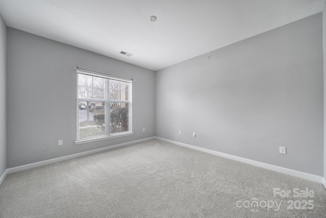 empty room with baseboards, visible vents, and carpet flooring