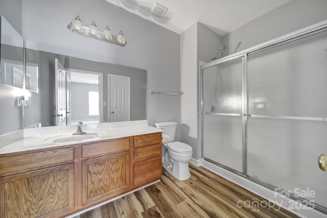 full bathroom featuring visible vents, toilet, vanity, a shower stall, and wood finished floors