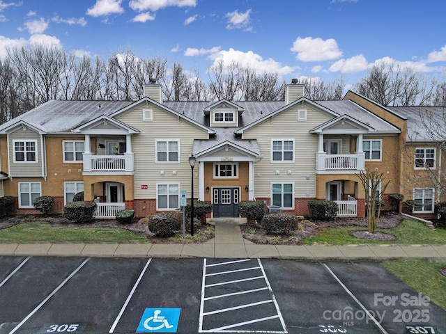 exterior space featuring uncovered parking, brick siding, a chimney, and a residential view