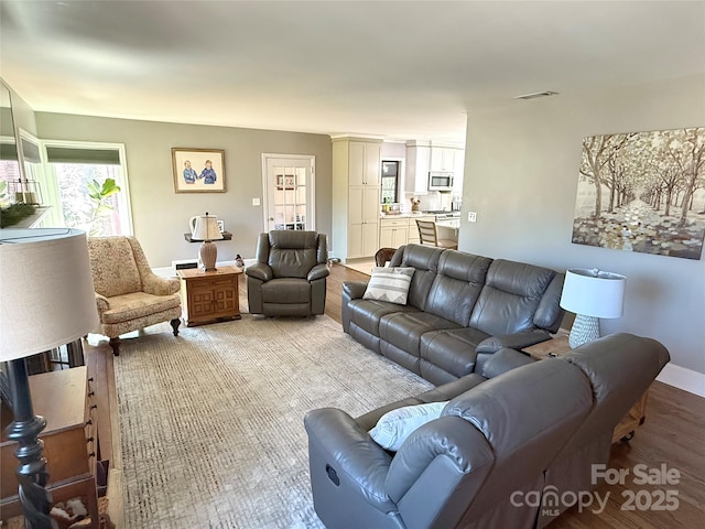 living room with visible vents, light wood-style flooring, and baseboards