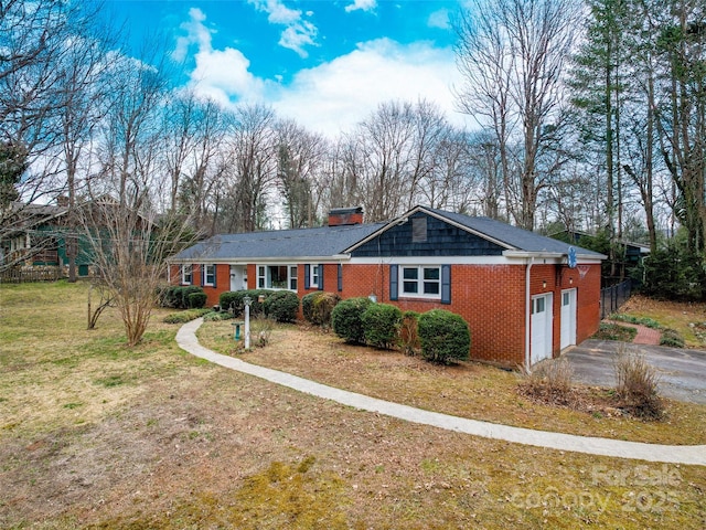 ranch-style home with an attached garage, a front yard, aphalt driveway, and brick siding