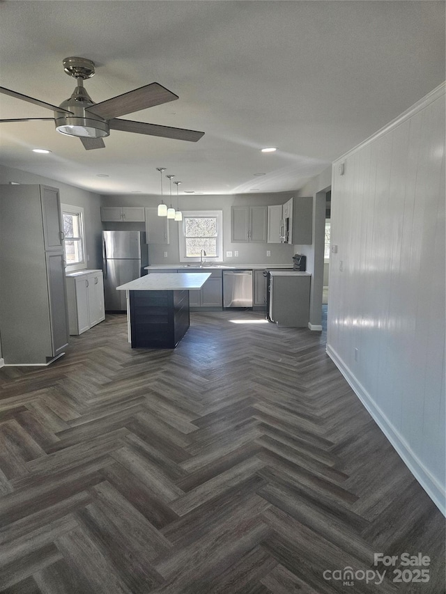 kitchen with gray cabinetry, stainless steel appliances, light countertops, a center island, and decorative light fixtures