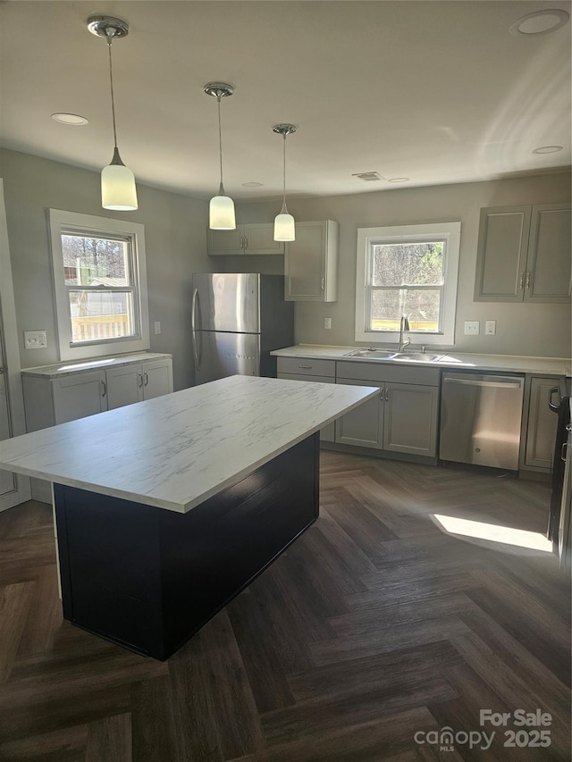 kitchen with stainless steel appliances, a sink, a center island, and pendant lighting