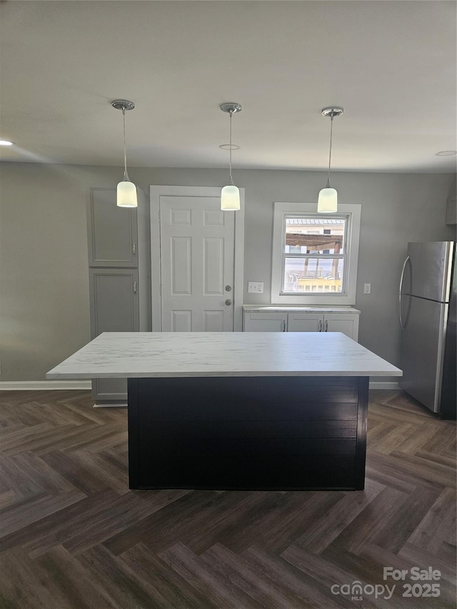 kitchen with freestanding refrigerator, pendant lighting, light countertops, and a kitchen island