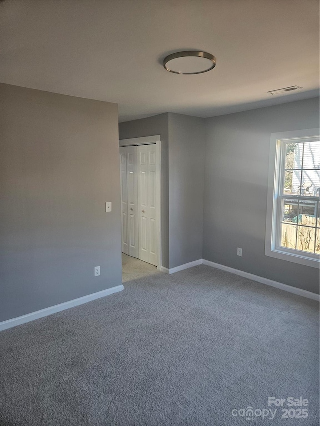 carpeted empty room featuring visible vents and baseboards