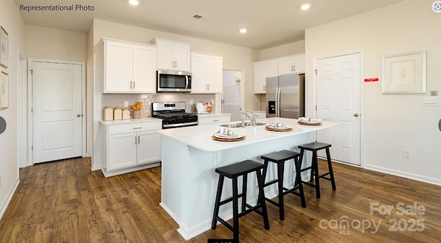 kitchen with a center island with sink, stainless steel appliances, light countertops, white cabinets, and a sink