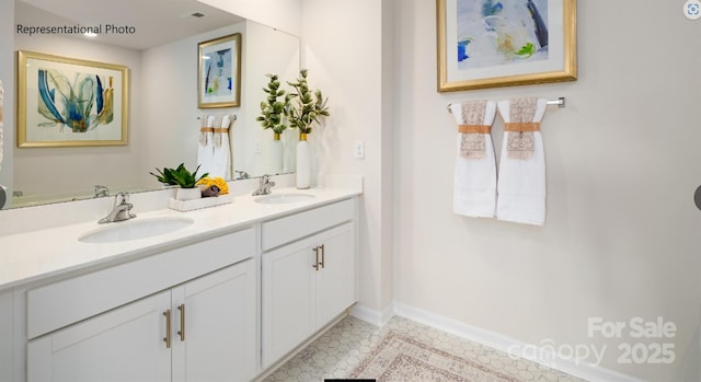 bathroom with double vanity, a sink, and baseboards