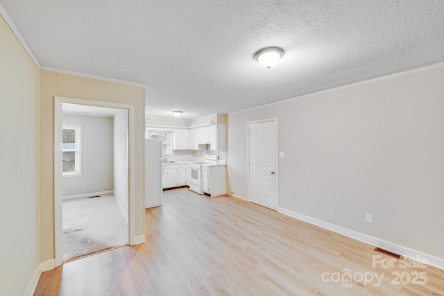 unfurnished living room with baseboards, visible vents, ornamental molding, a textured ceiling, and light wood-style floors