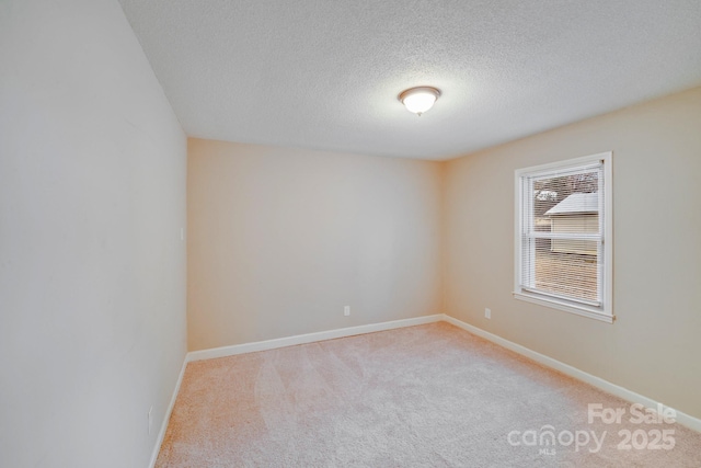 unfurnished room featuring baseboards, a textured ceiling, and light colored carpet