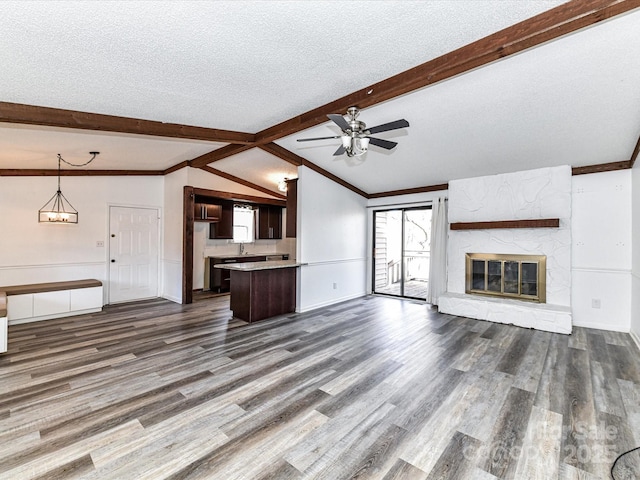 unfurnished living room with a textured ceiling, lofted ceiling with beams, a high end fireplace, a ceiling fan, and dark wood-style floors