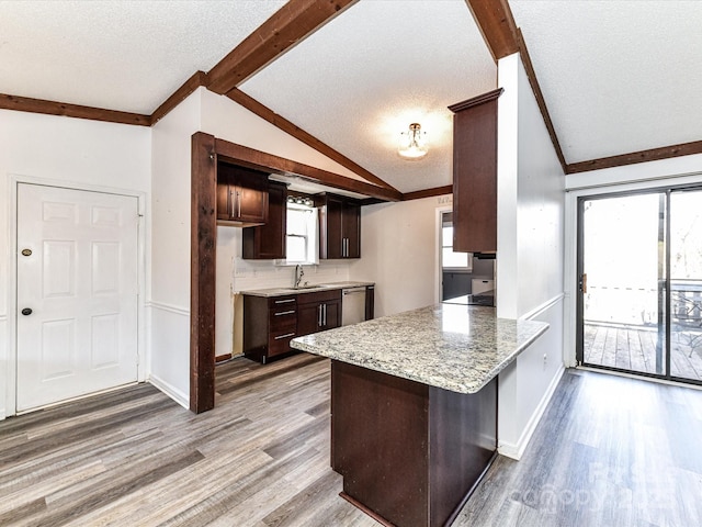 kitchen featuring lofted ceiling with beams, wood finished floors, a peninsula, dark brown cabinets, and a sink