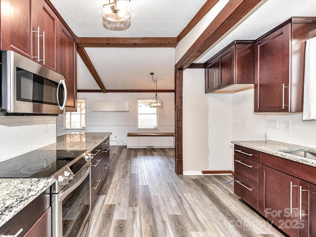 kitchen featuring appliances with stainless steel finishes, wood finished floors, vaulted ceiling with beams, light stone countertops, and a textured ceiling