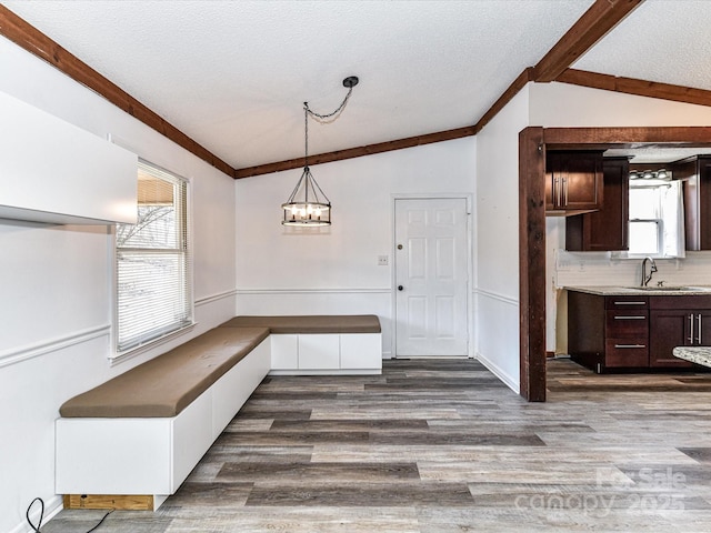 unfurnished dining area with vaulted ceiling with beams, plenty of natural light, a sink, and dark wood finished floors