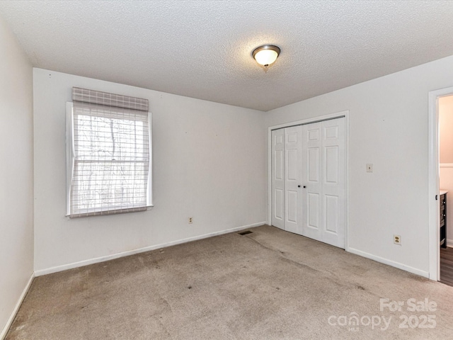 unfurnished bedroom featuring a textured ceiling, a closet, carpet, and baseboards