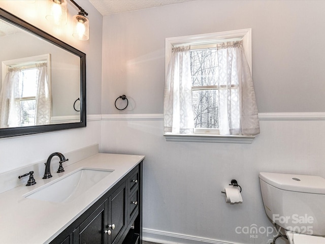 bathroom with a textured ceiling, vanity, and toilet