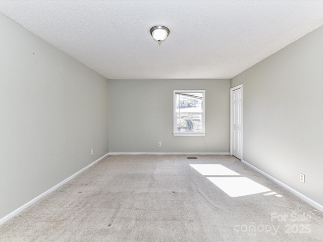 carpeted spare room with a textured ceiling, visible vents, and baseboards