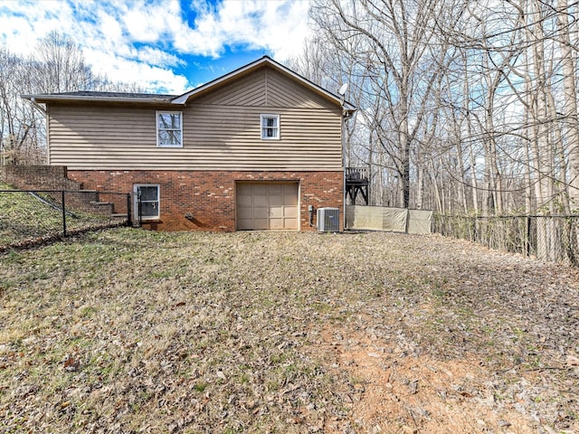 view of home's exterior with a garage, brick siding, fence, and central AC unit