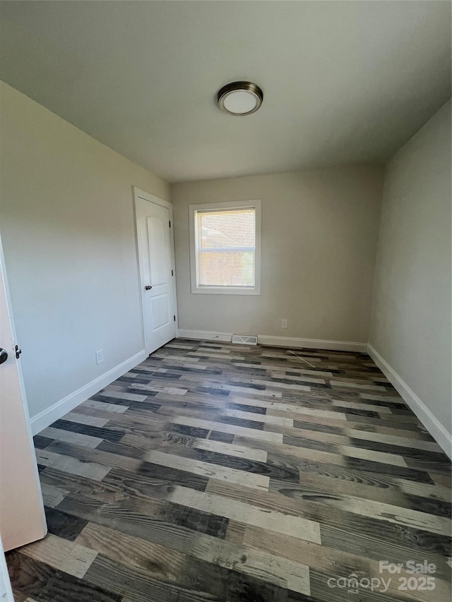 spare room with baseboards, visible vents, and wood finished floors