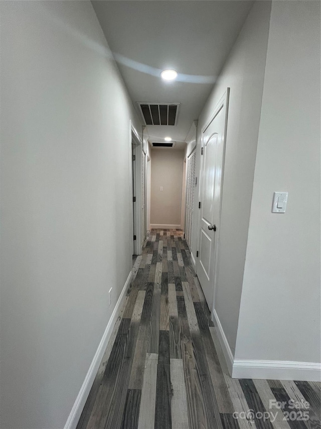 corridor with visible vents, baseboards, and wood finished floors