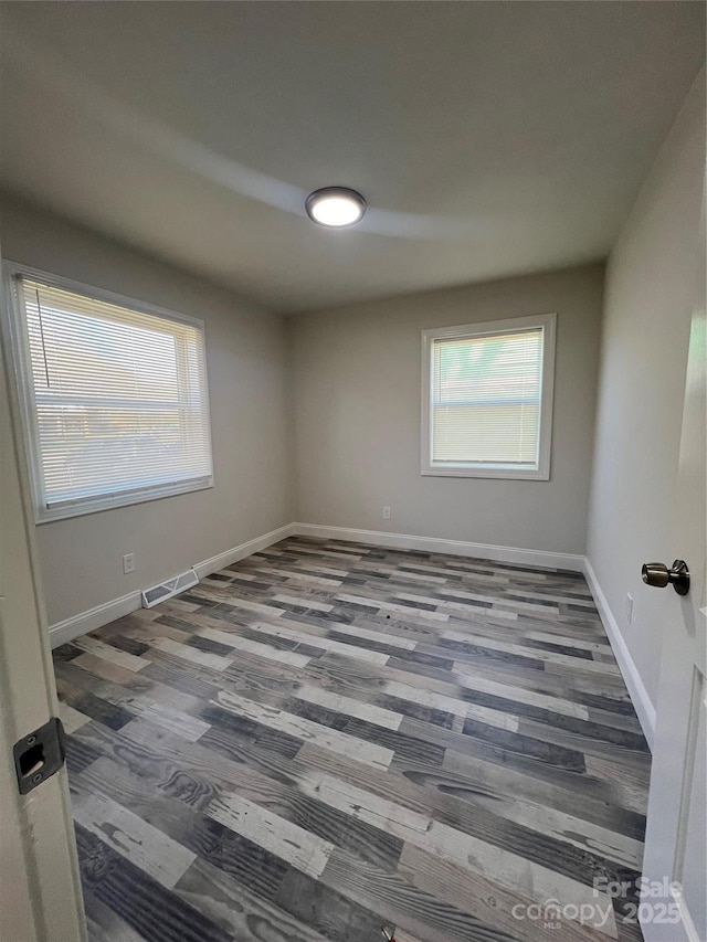 unfurnished room with visible vents, baseboards, and wood finished floors