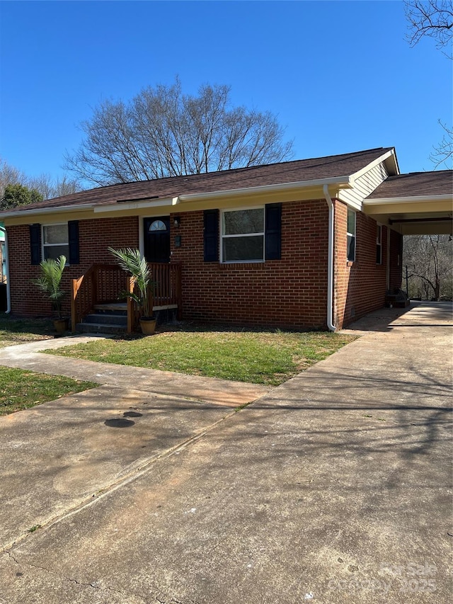 ranch-style home featuring concrete driveway, brick siding, a front lawn, and an attached carport