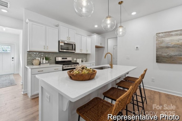 116 Shay Crossing Rd Unit 2P, Salisbury, NC 28144 - kitchen featuring stainless steel appliances, a breakfast bar, decorative backsplash, white cabinets, and a kitchen island with sink