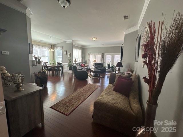 living room featuring crown molding, visible vents, plenty of natural light, and wood finished floors