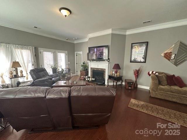 living area with baseboards, visible vents, wood finished floors, crown molding, and a fireplace