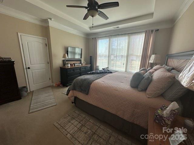 bedroom with light carpet, ceiling fan, a tray ceiling, and crown molding