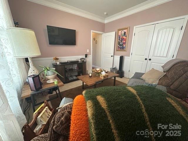 bedroom with a closet, crown molding, and wainscoting