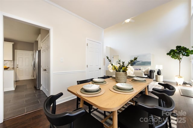 dining area with dark wood-style floors, crown molding, and baseboards