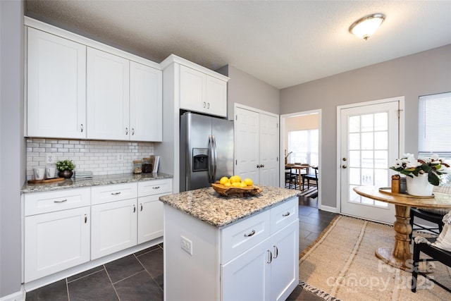 kitchen featuring light stone counters, white cabinets, backsplash, and stainless steel fridge with ice dispenser