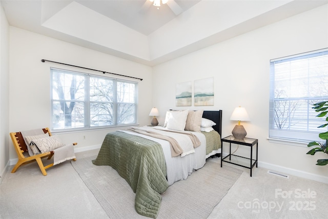 bedroom featuring a raised ceiling, visible vents, light carpet, and baseboards