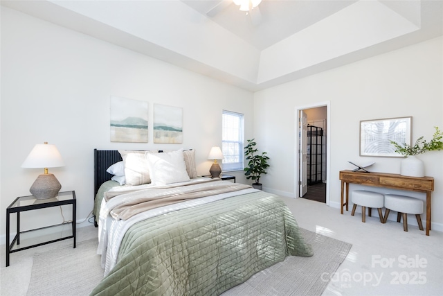 bedroom featuring a ceiling fan, a raised ceiling, light carpet, and baseboards