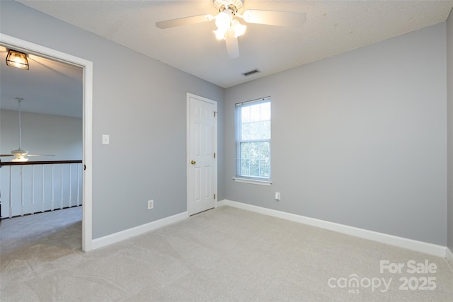 empty room with visible vents, baseboards, a textured ceiling, and light colored carpet