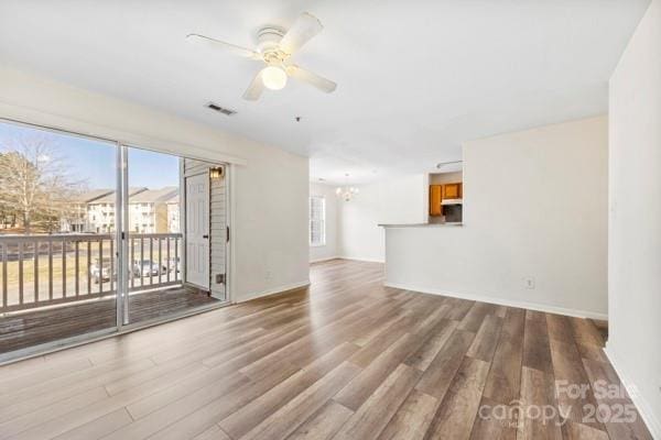 unfurnished living room with visible vents, wood finished floors, and ceiling fan with notable chandelier